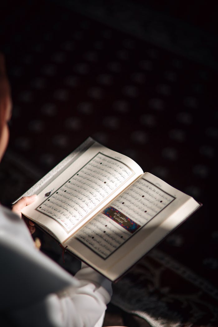 A person reading the Koran in a spiritual and sunlit environment, symbolizing peace and devotion.